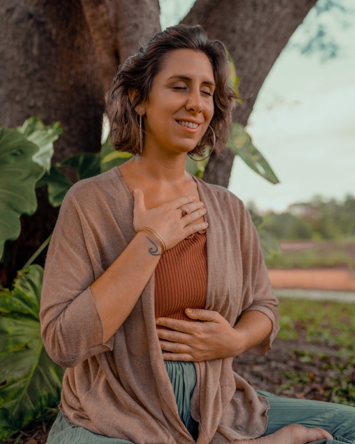 Bénédicte Donet en méditation, la main sur le cœur, sous un arbre